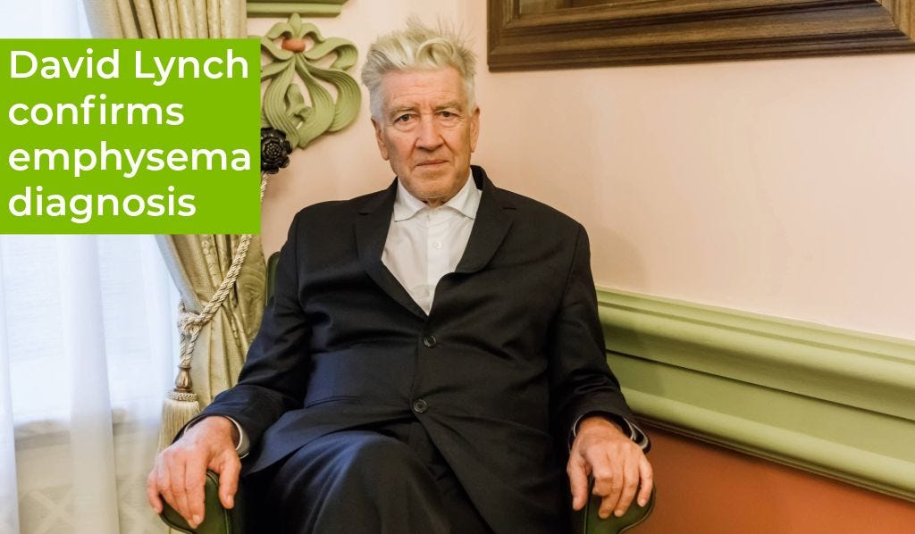 David Lynch sitting in a chair, wearing a suit