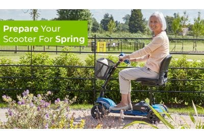 A lady riding her mobility scooter along a path in Spring sunshine, surrounded by flowers and plants in a park