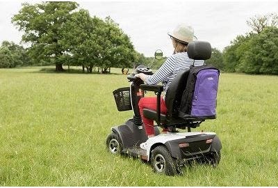 woman riding a mobility scooter in a grassy park