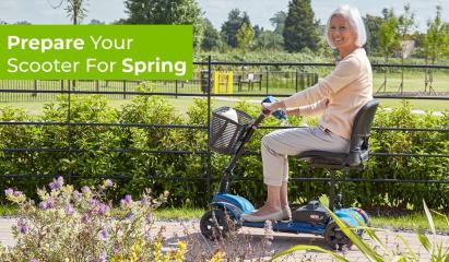 A lady riding her mobility scooter along a path in Spring sunshine, surrounded by flowers and plants in a park