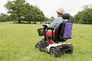 woman riding a mobility scooter in a grassy park