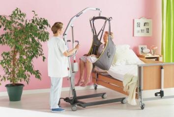 nurse using hoist to move patient to bed