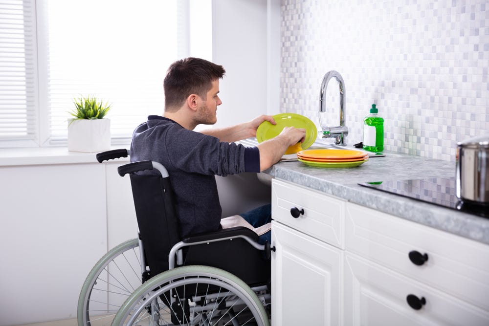 Man in wheelchair washing up in kitchen