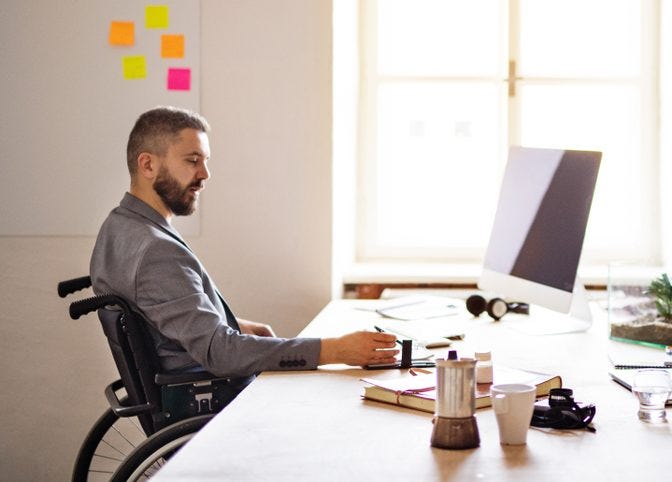 man in wheelchair sitting at desk with good posture