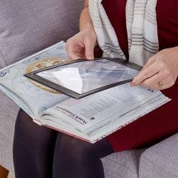 woman using a Sheet Magnifier to read a large book