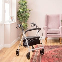 Secco 4 Rollator inside a room with a rug, plants and armchair