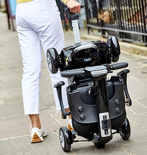 man carrying a folded mobility scooter