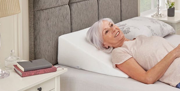 Woman using a bed wedge on a bed