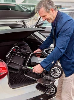 man putting a Zora folding powerchair in a car boot
