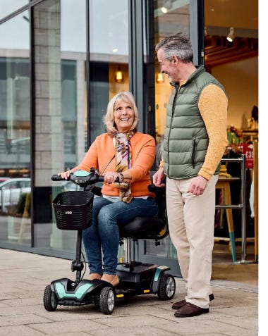 man and woman on a mobility scooter leaving a shop