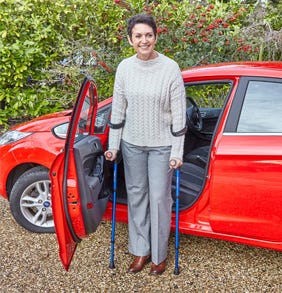 woman standing next to car with crutches