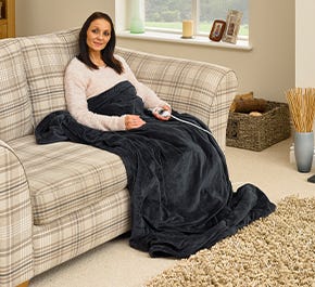Woman sitting under Comfi Electric Heated Blanket on sofa