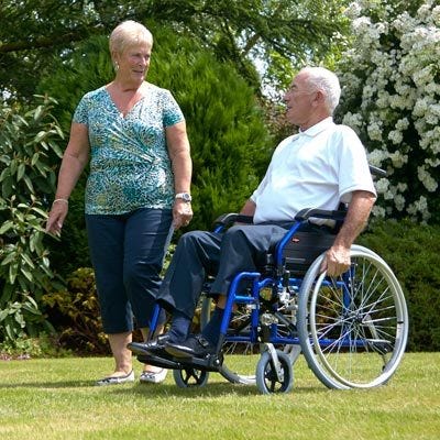 man in wheelchair on a lawn with woman, chatting